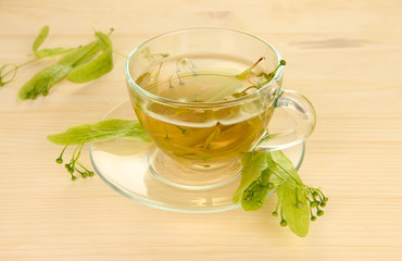 Glass cup of tea with linden on wooden table close-up