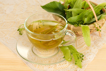 Glass cup of tea with linden on wooden table close-up