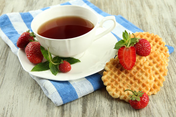 Cup of tea with cookies and strawberries on table close-up