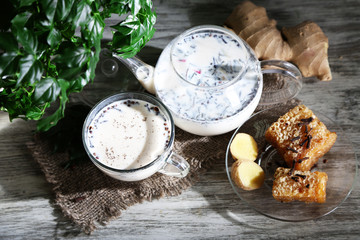 Teapot and cup of tea with milk and spices