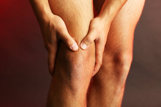 Young Man With Knee Pain On Dark Background