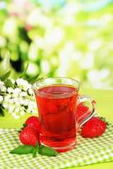 Delicious strawberry tea on table on bright background
