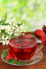 Delicious strawberry tea on table on bright background