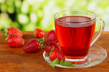Delicious strawberry tea on table on bright background