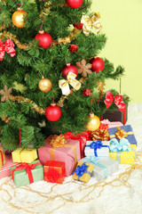 Decorated Christmas tree with gifts on green wall background