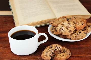 Cup of coffee with cookies and books on wooden background