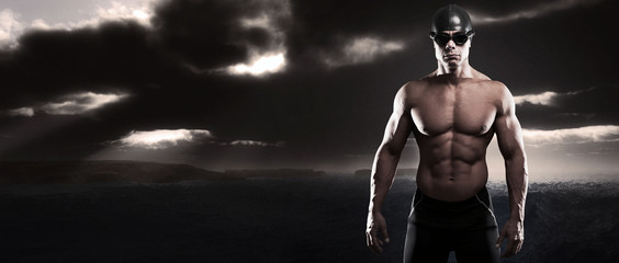 Muscled swimmer man with cap and glasses outdoor at rough sea wi