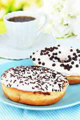Sweet donuts with cup of tea on table close-up