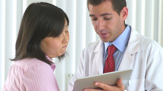 Doctor reviewing test results on tablet with patient