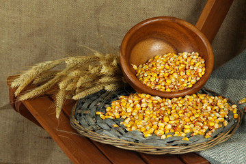 Bowl of corns on wicker stand on chair on sackcloth background