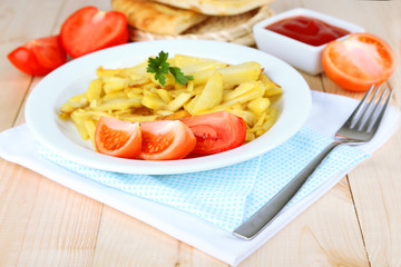 Fried potatoes on plate on wooden table close-up