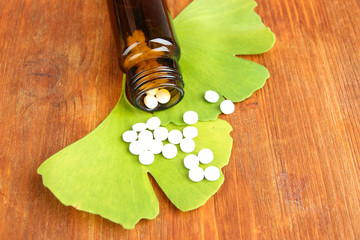 Ginkgo biloba leaves and medicine bottle on wooden background