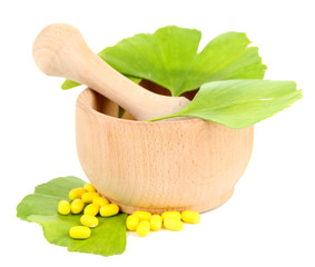 Ginkgo biloba leaves in mortar and pills isolated on white