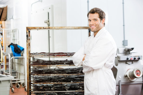 Confident Worker Standing By Rack Of Beef Jerky At Shop