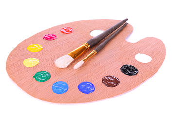 Wooden art palette with paint and brushes isolated on white