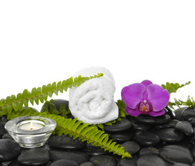 Obraz na płótnie Canvas towel with green fern and pink orchid, candle on pebbles