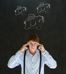 Businessman with chalk flying money piggy banks on blackboard