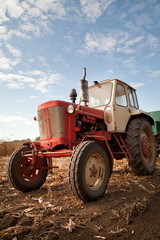old tractor in field, against a cloudy sky