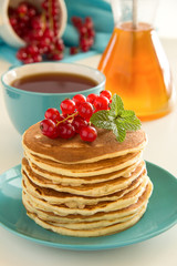 Homemade pancakes with honey and berries on a wooden table.
