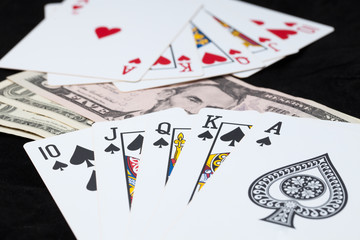 Royal Flush and bank note on black background