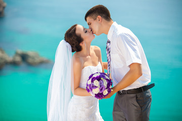 wedding couple stands on a cliff, blue sea on background