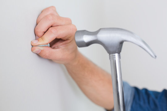Extreme Close up of hand hammering nail in wall