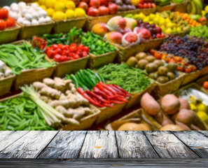 Background with empty wooden table and blured fruits and vegetab