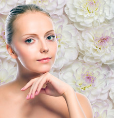 Obraz na płótnie Canvas Young girl against white flowers background. Perfect skin