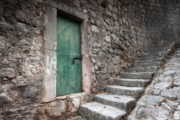 Fototapeta na wymiar Old locked green door and stone stairway in Perast town, Montene