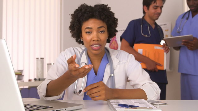 African American doctor talking with colleagues in background