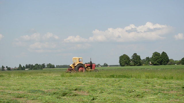 farmer in small tractor cutting the grass