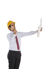 Male architect holding a blueprint and thinking