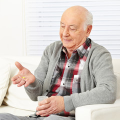 Senior zu Hause nimmt Medikamente ein