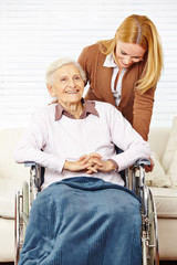 Seniorin im Rollstuhl wird von Tochter betreut