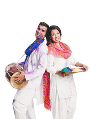 Couple celebrating Holi with colors and a drum