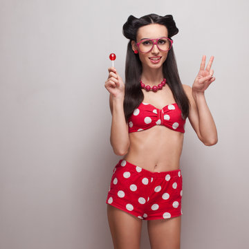 Smiling pinup model posing with red candy
