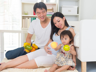 asian pregnant mother with her family at the living room