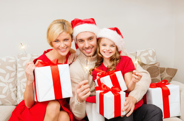 smiling family holding gift boxes and sparkles
