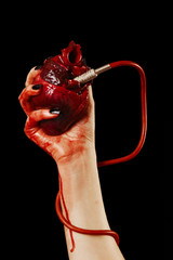 Human heart in hand with pipe, red cable isolated on black © barelko.com