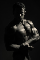 Obraz na płótnie Canvas Young sports male with a naked torso against a dark background.