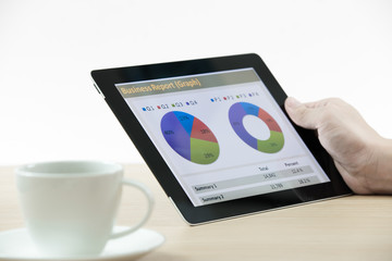 Businessman holding digital tablet and business report