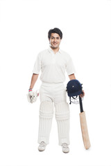 Batsman holding a cricket bat with sports helmet and smiling