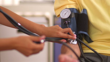 Mexican nurse checking patient's blood pressure - Powered by Adobe