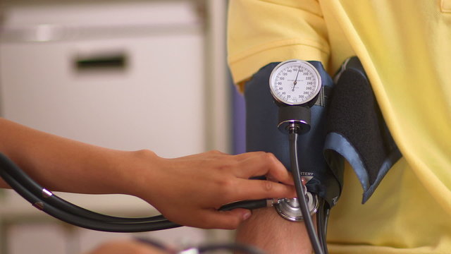 Hispanic Nurse Checking Patient's Blood Pressure