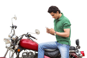 Fototapeta na wymiar Man text messaging on a mobile phone while sitting on a motorcycle