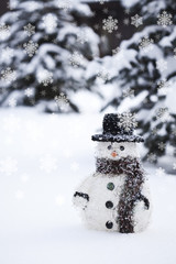 Toy snowman in a hat on snow