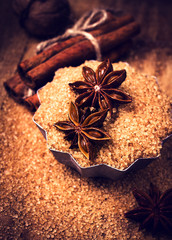 Cinnamon sticks, nuts and star anise on brown sugar, macro. Baki