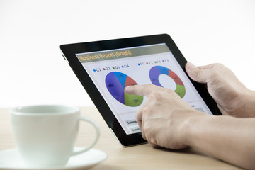 Businessman holding digital tablet and business report