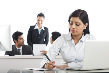 Businesswoman working in the office with her colleagues in the background