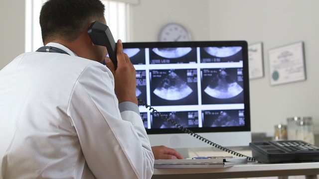 Mexican doctor viewing sonogram on computer while talking on pho